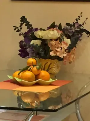 a vase with flowers and oranges on a glass table at AMN Center Apartment in Belgrade