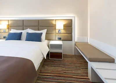 a hotel room with a bed and a bench at Hotel TESLA - Smart Stay Garni in Belgrade