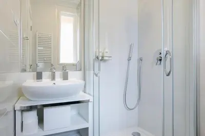 a white bathroom with a sink and a shower at Urban Downtown Apartment in Belgrade