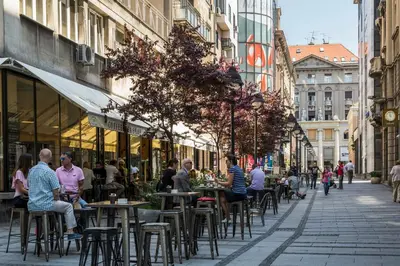 a group of people sitting at tables on a city street at Dominic Smart & Luxury Suites - Republic Square in Belgrade