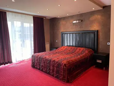 a bedroom with a large bed with a red bedspread at Vila Srbija Beograd in Meljak