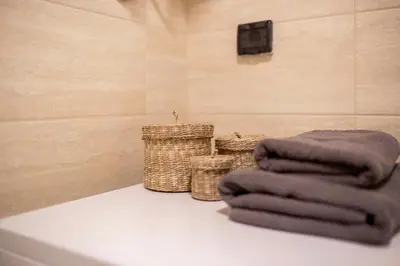 a bathroom with three towels and two baskets at Leo Modern Urban Stay, Self Check-In, Free Garage in Belgrade