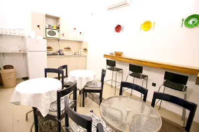 a dining room with tables and chairs and a kitchen at Hostel 1910 in Belgrade