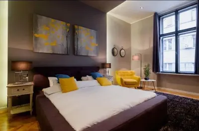 a bedroom with a large bed and a yellow chair at Lella Apartment - Pedestrian zone & Charming balcony in Belgrade