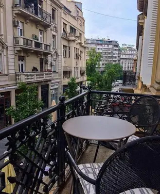 a table and chairs on a balcony with buildings at Lella Apartment - Pedestrian zone & Charming balcony in Belgrade