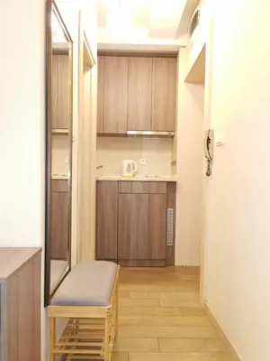 a small kitchen with wooden cabinets and a bench at 1A Moment Apartment in Belgrade