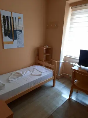 a bedroom with a bed and a desk and a window at Petar Drapšin Hostel in Belgrade
