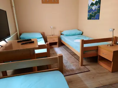 a room with two beds and a desk and a tv at Petar Drapšin Hostel in Belgrade