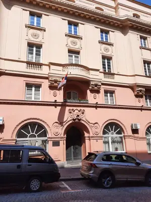 two cars parked in front of a pink building at Petar Drapšin Hostel in Belgrade
