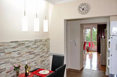a kitchen and dining room with a table and a clock on the wall at Kristi Lux Apartment Center Free Parking Fast WiFi in Belgrade