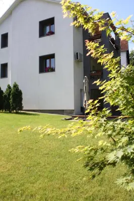 a white building with windows and a green yard at Apartmani15 in Arandjelovac