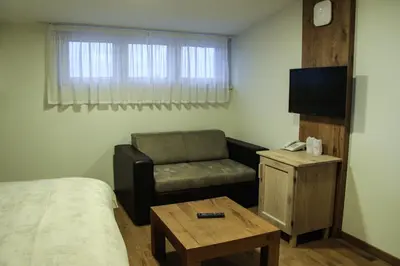 a room with a bed and a chair and a television at B&B Villa Panuka in Pančevo
