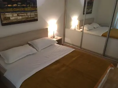 a bedroom with a large white bed and two mirrors at Apartment Gorki in Belgrade