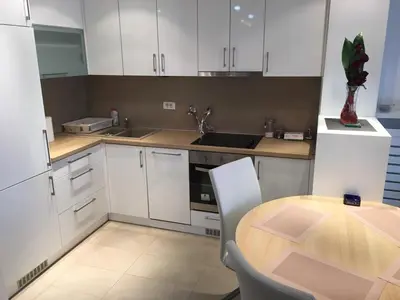 a kitchen with white cabinets and a wooden table at Apartment Gorki in Belgrade