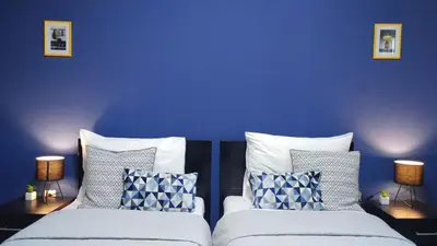 a bedroom with blue walls and two beds with pillows at Apartment Wake Up For 4 in Belgrade