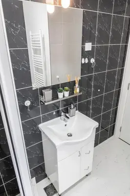 a black tiled bathroom with a sink and a mirror at Apartment Wake Up For 4 in Belgrade