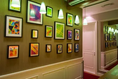 a wall with a bunch of framed art on it at B&B Wimbledon Garni Concept in Belgrade