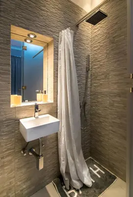 a bathroom with a shower with a sink and a mirror at Nusha Apartments in Belgrade