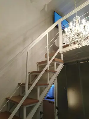 a white staircase in a room with a chandelier at Nusha Apartments in Belgrade