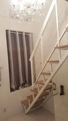 a white staircase in a room with a chandelier at Nusha Apartments in Belgrade