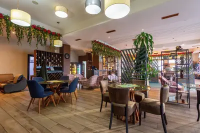 a restaurant with tables and chairs and plants at Hotel Crystal in Pećinci