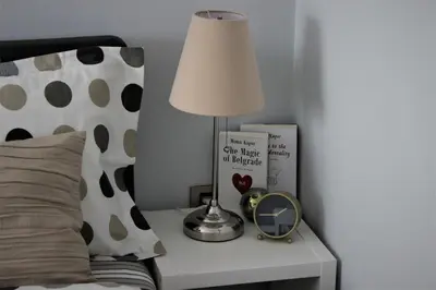 a lamp on a table next to a bed with a clock at Apartment Skadarlija FREE parking in Belgrade