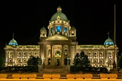 a large building with a tower with blue lights on it at Parliament Apartment in Belgrade