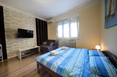 a bedroom with a bed and a tv and a couch at Parliament Apartment in Belgrade
