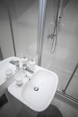 a white bathroom with a sink and a shower at Aria Royal Nusic apartment in Belgrade