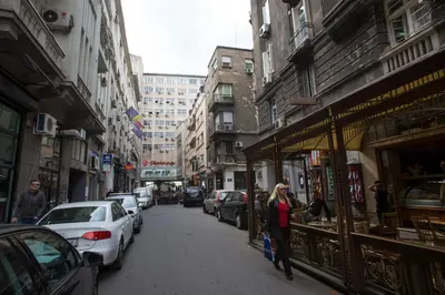a woman walking down a city street with cars at Aria Royal Nusic apartment in Belgrade