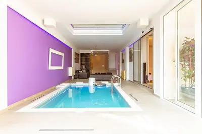 a swimming pool in a house with purple walls at #1 Lux Villa with Pool, Gameroom, Spa, Zen Yard #Free airport transport# in Belgrade