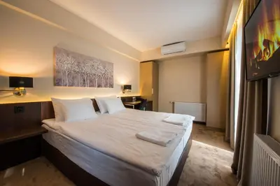 a bedroom with a large bed with white sheets and pillows at Hotel Spa Grad in Kovin