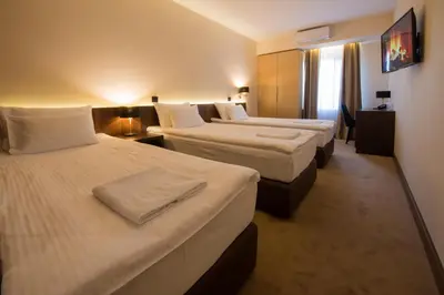 a hotel room with three beds and a window at Hotel Spa Grad in Kovin