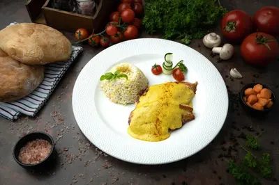 a white plate with food on a table with tomatoes and bread at Hotel Spa Grad in Kovin