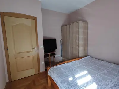 a bedroom with a bed and a door and a television at Apartment StefanA in Belgrade