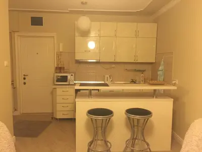 a kitchen with white cabinets and two bar stools at Apartman Skadarlija in Belgrade