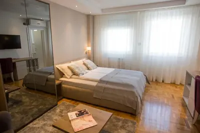 a bedroom with a large bed and a mirror at Dia Belgrade Arena Apartment in Belgrade