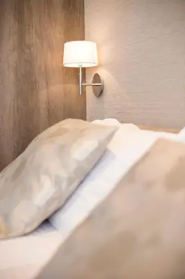 a bed with a pillow and a lamp on a wall at Dia Belgrade Arena Apartment in Belgrade