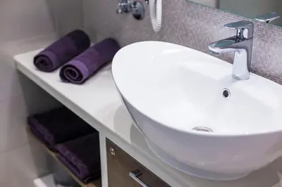 a bathroom with a white sink and purple towels at Dia Belgrade Arena Apartment in Belgrade