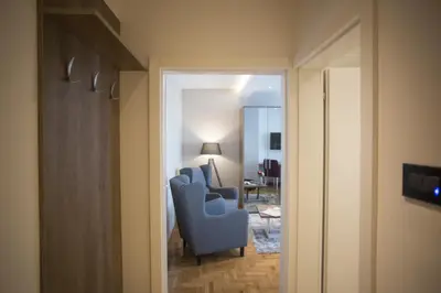 a room with two blue chairs and a living room at Dia Belgrade Arena Apartment in Belgrade