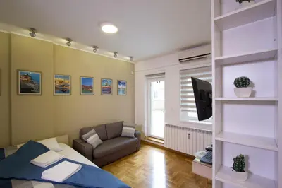 a bedroom with a bed and a couch and a tv at Lux Life Apartment in Belgrade