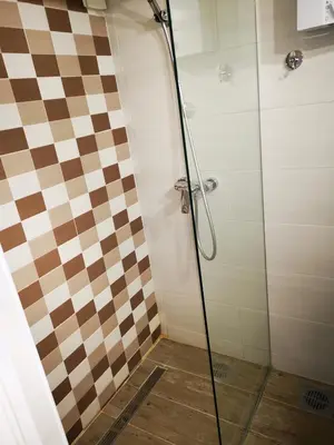 a bathroom with a shower with a checkered wall at Dream Apt with parking in Belgrade
