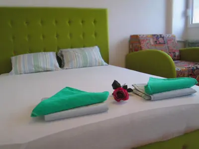 a bed with green pillows and a red rose on it at Dream Apt with parking in Belgrade