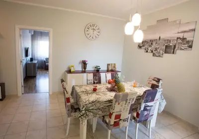 a dining room table with chairs and a clock on the wall at Central City Apartments in Belgrade