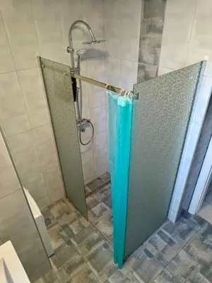 a shower stall with a blue umbrella in a bathroom at Central City Apartments in Belgrade