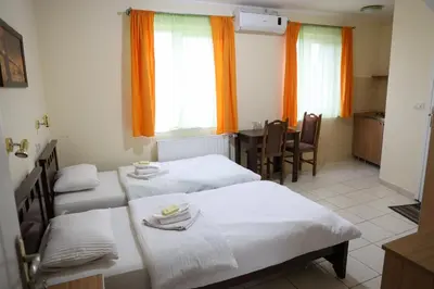 a room with two beds and a table and chairs at Marex Centar in Jabuka