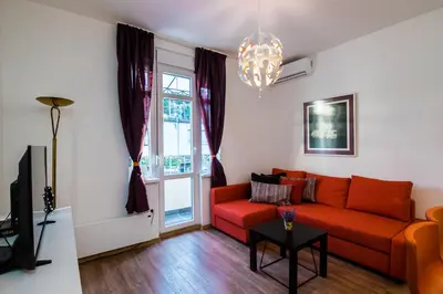 a living room with a red couch and a window at Bright City Center Apartment with Balcony in Belgrade