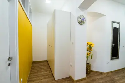 a hallway with a clock on the wall and a vase of flowers at Bright City Center Apartment with Balcony in Belgrade