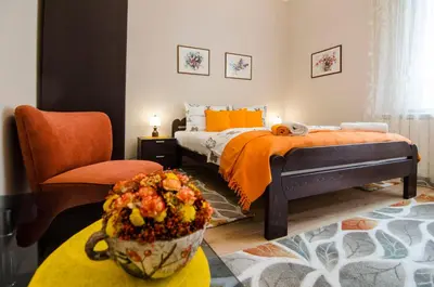 a bedroom with a bed with an orange blanket and a chair at Villa Rose in Belgrade