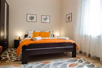 a bedroom with a bed with an orange blanket at Villa Rose in Belgrade